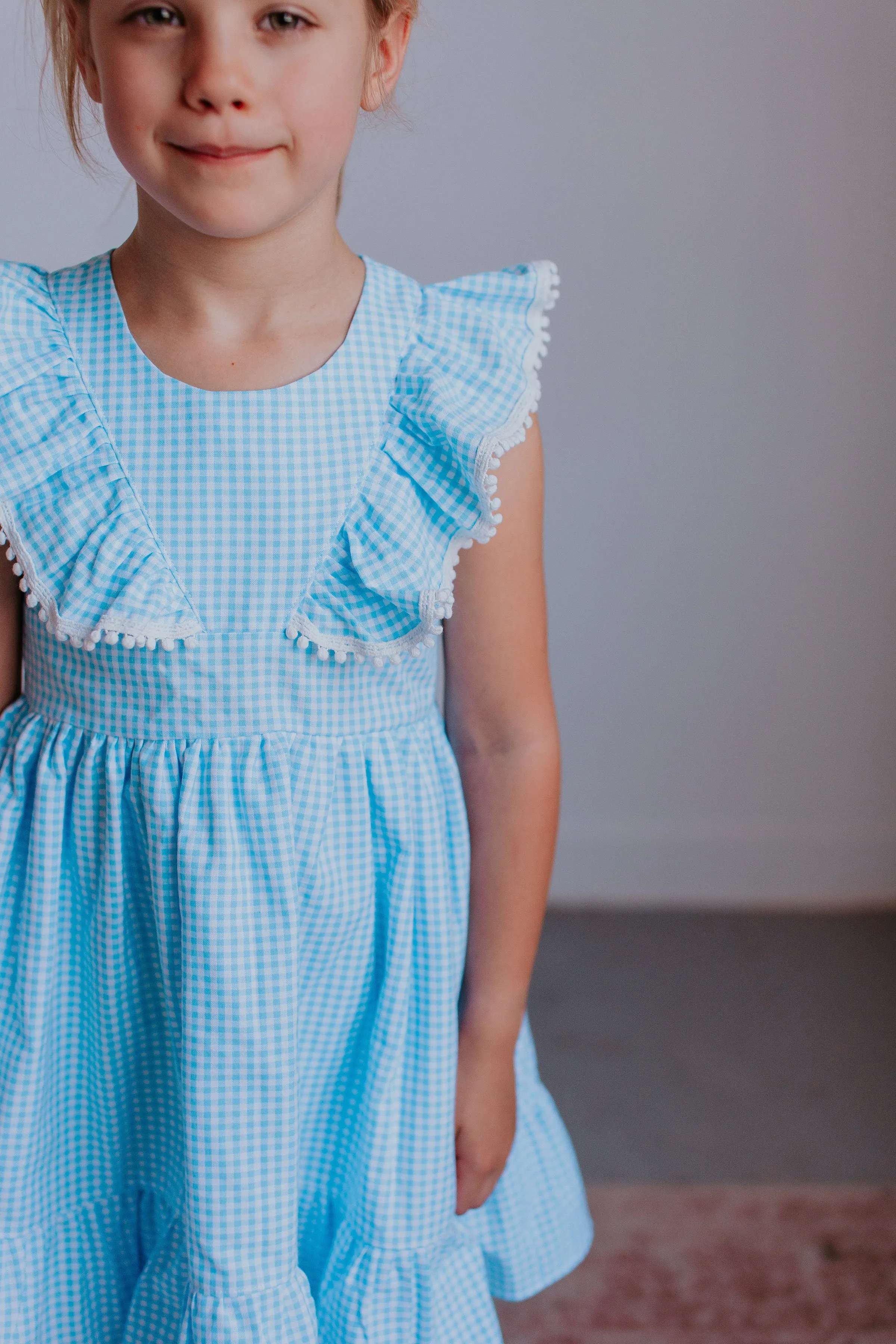 Little Girl's Blue Gingham Pinafore Dress with Pom Pom Trim
