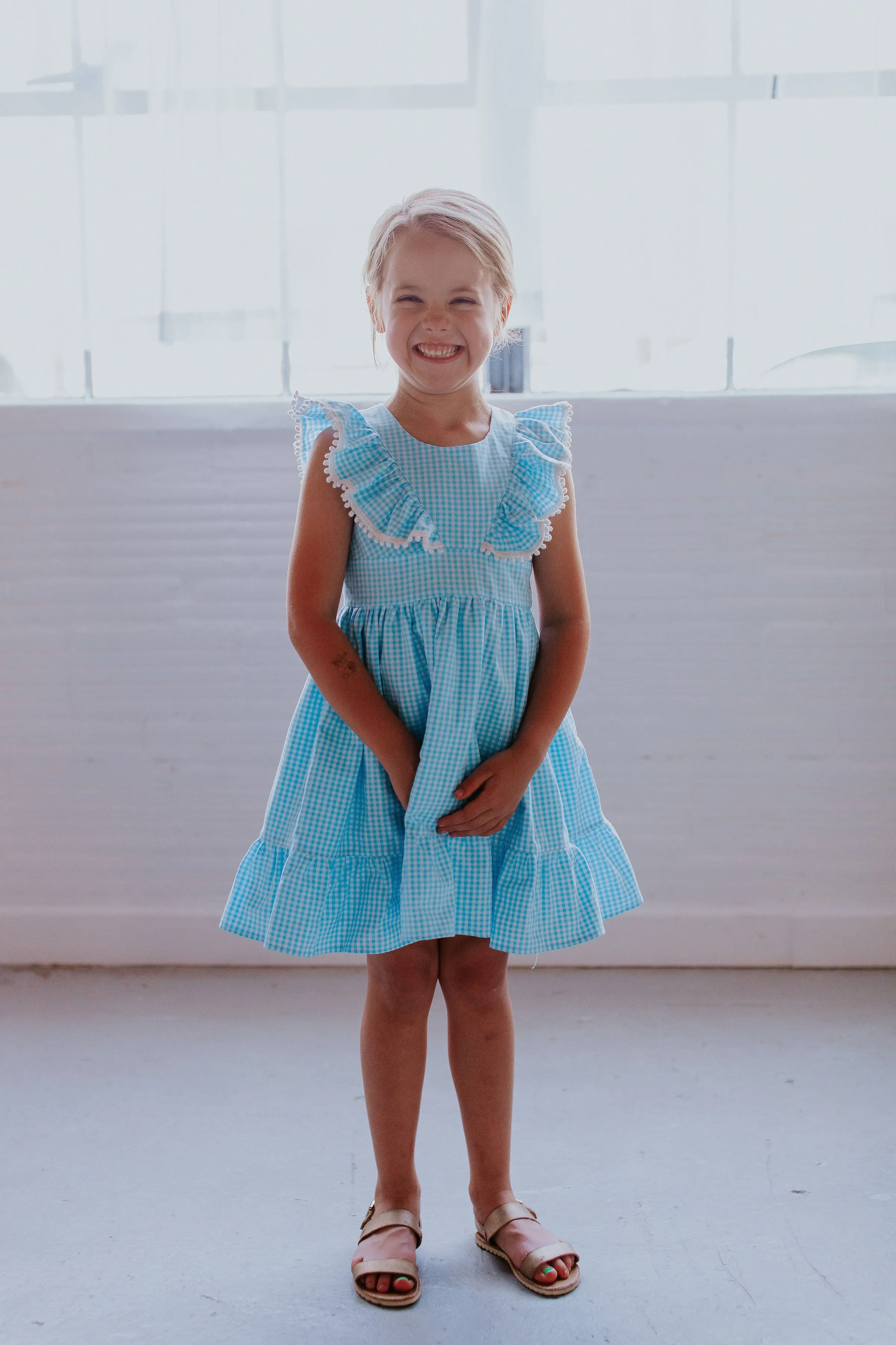 Little Girl's Blue Gingham Pinafore Dress with Pom Pom Trim