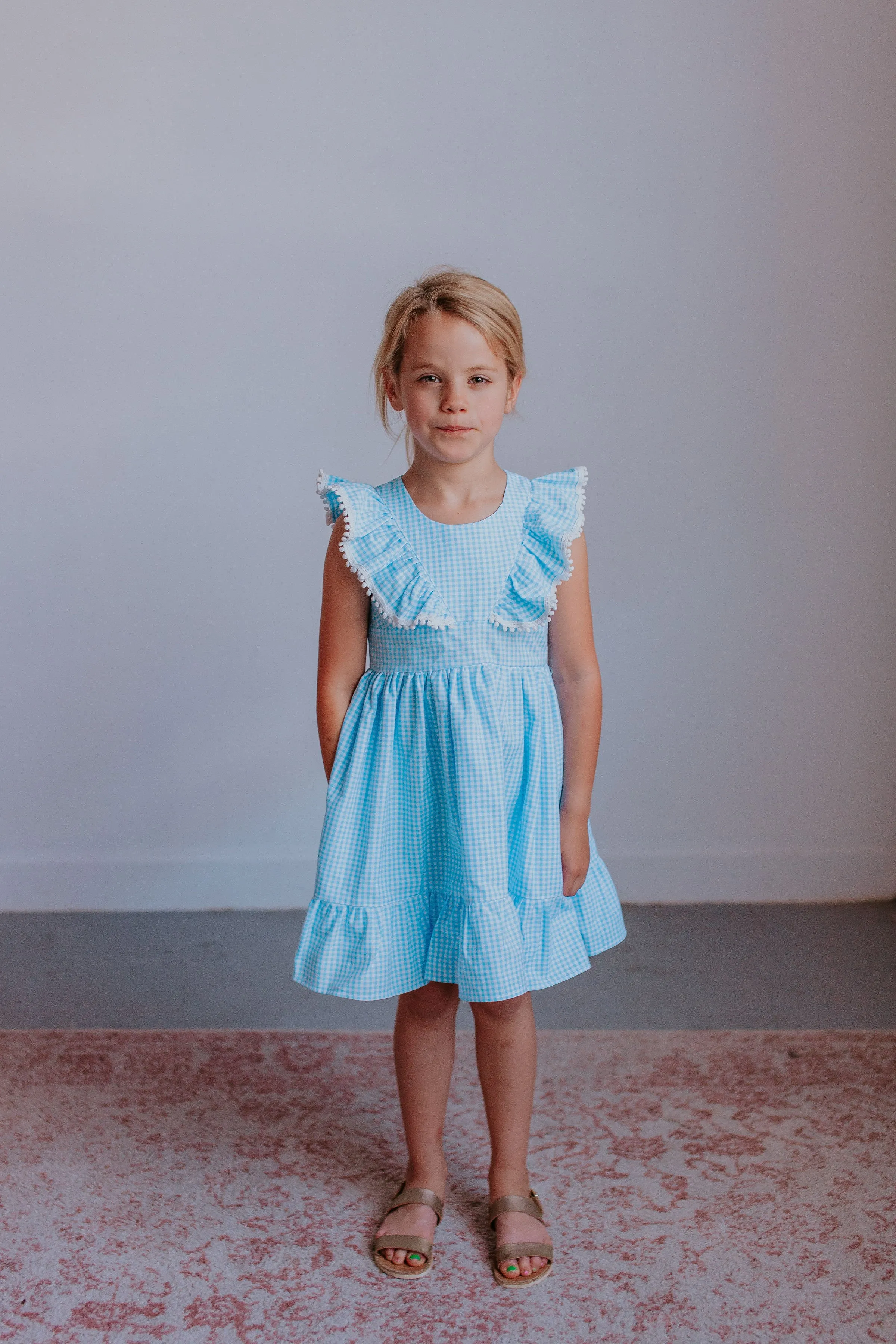 Little Girl's Blue Gingham Pinafore Dress with Pom Pom Trim