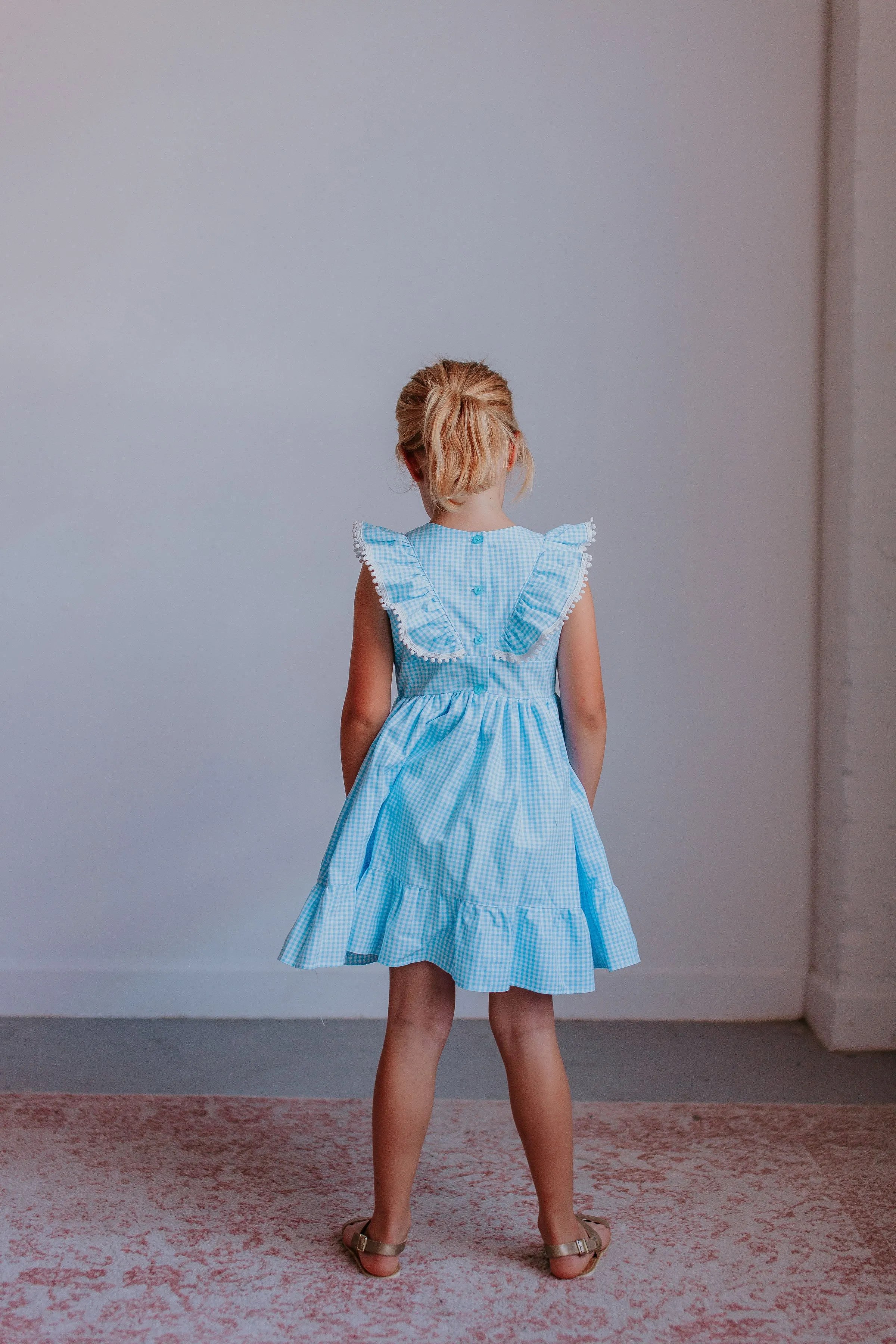 Little Girl's Blue Gingham Pinafore Dress with Pom Pom Trim